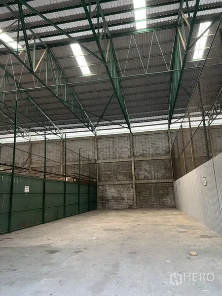 Warehouse for rent in Prawet, Bangkok - High-ceiling warehouse bay with skylights, green steel framing and partitioned storage.