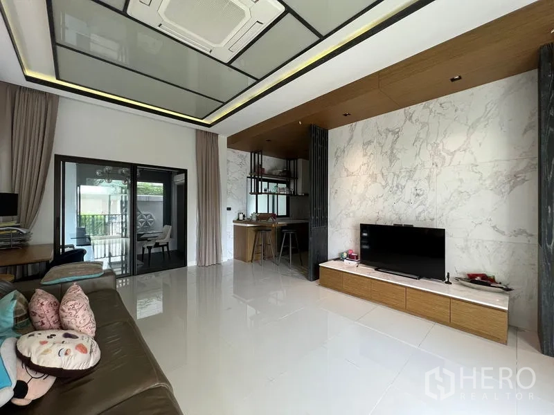 Townhouse for rent in Saphan Sung, Bangkok - Living area featuring marble accent wall, TV cabinet, and view toward the kitchen.
