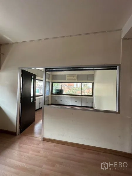 Office Space for rent in Khlong Toei, Bangkok - Interior partition window looking into a workspace with cabinets and a wide exterior window.