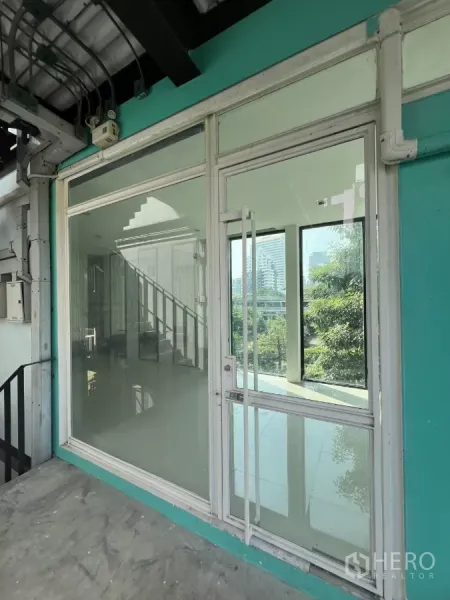 零售空间 出租在Watthana, Bangkok - 三楼零售门面，玻璃大门与青绿色外墙，配楼梯出入并可眺望绿景。