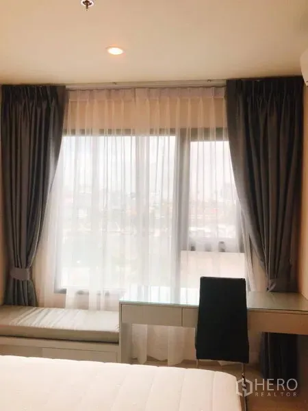 คอนโด ให้เช่าในHuai Khwang, Bangkok - ห้องนอนมีหน้าต่างบานใหญ่ ผ้าม่านโปร่ง โต๊ะทำงาน และเบย์วินโดว์นั่งเล่น