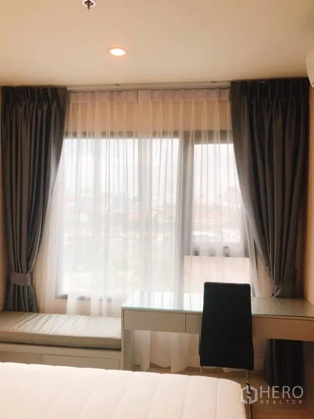 คอนโด ให้เช่าในHuai Khwang, Bangkok - ห้องนอนมีหน้าต่างบานใหญ่ ผ้าม่านโปร่ง โต๊ะทำงาน และเบย์วินโดว์นั่งเล่น