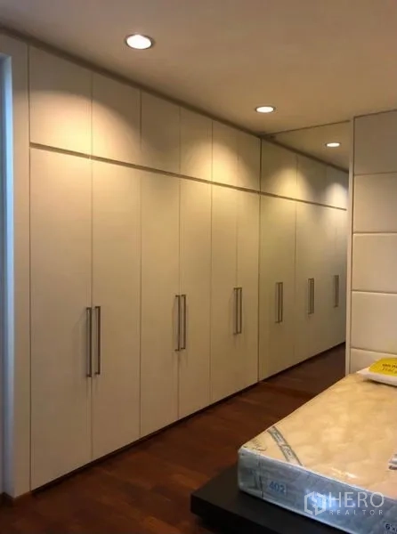 Townhouse for rent in Chatuchak, Bangkok - Primary bedroom featuring a long wall of built-in wardrobes with recessed lighting.