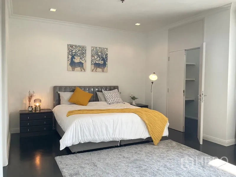 Apartment for rent in Sathon, Bangkok - Primary bedroom with king bed, nightstands and walk‑in closet entrance.