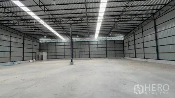 Warehouse for rent in Khlong Toei, Bangkok - Panoramic view of empty warehouse with bright roof skylights and ample loading area.