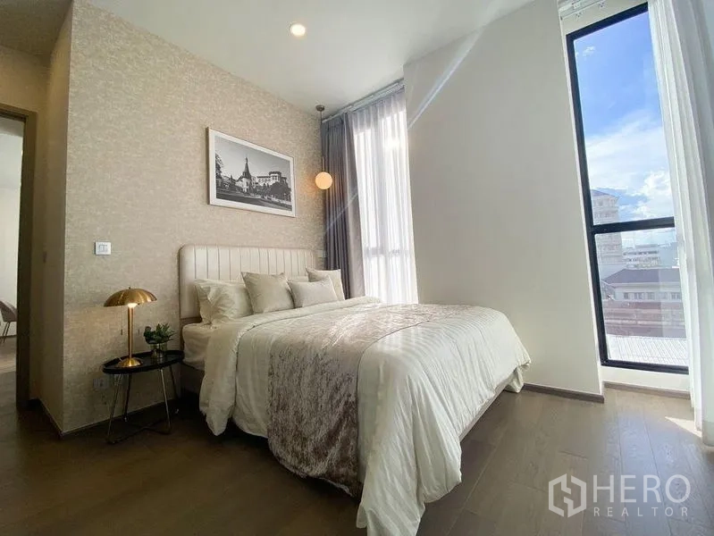 公寓 出租在Ratchathewi, Bangkok - 主卧配大窗与城市景观，柔和灯光与浅色床品，舒适温馨。
