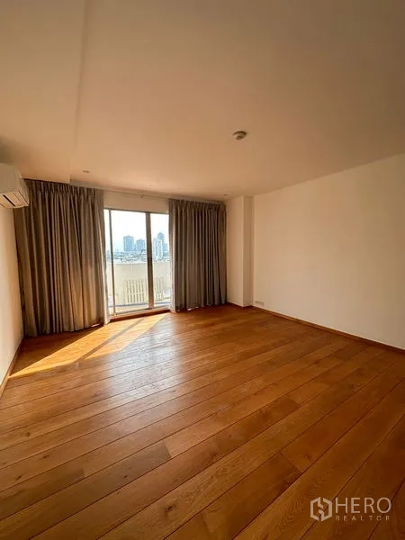 Condominium for rent in Khlong Toei, Bangkok - Spacious bedroom with wood floors and balcony access through sliding doors overlooking the city.