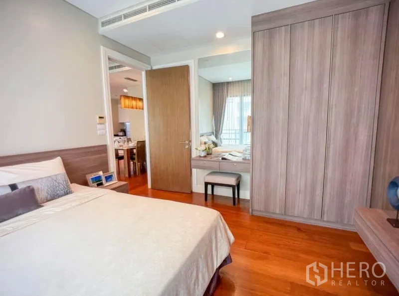 Condominium for rent in Khlong Toei, Bangkok - Bedroom storage with full-height wardrobes and a dressing table with mirror and stool.