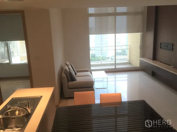 คอนโด ให้เช่าในSathon, Bangkok - ห้องนั่งเล่นสว่าง โซฟา ผนังทีวีบิลท์อิน และประตูกระจกสไลด์ออกสู่ระเบียงชมวิวเมือง