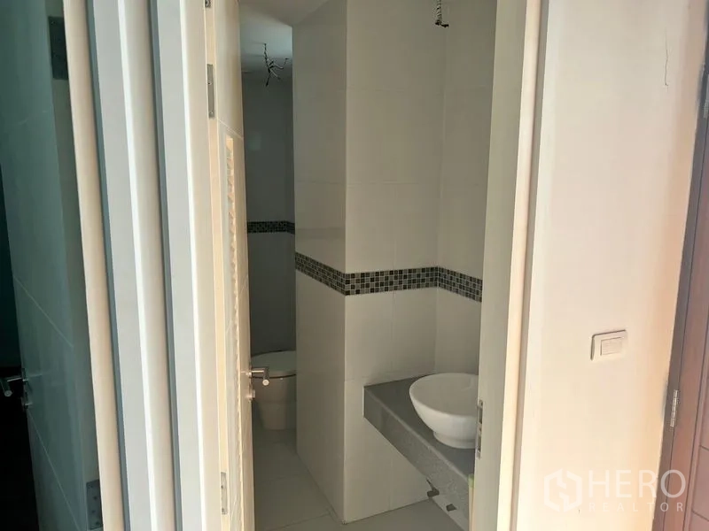 Condominium for rent in Bang Kho Laem, Bangkok - Compact bathroom with vessel sink on a stone counter and mosaic tile accent with separate toilet area.