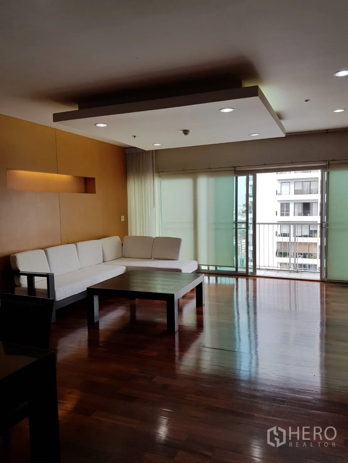 公寓 出租或出售在Watthana, Bangkok - 宽敞客厅设L形沙发、筒灯照明，并连接阳台