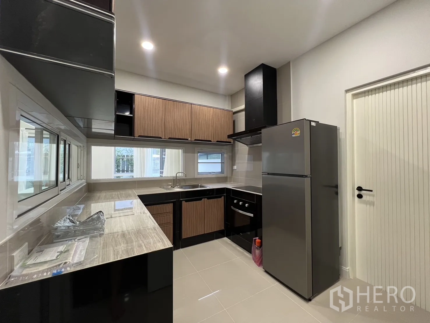 Detached House for rent in Saphan Sung, Bangkok - Kitchen with refrigerator, oven, cooker hood and glossy floor tiles.
