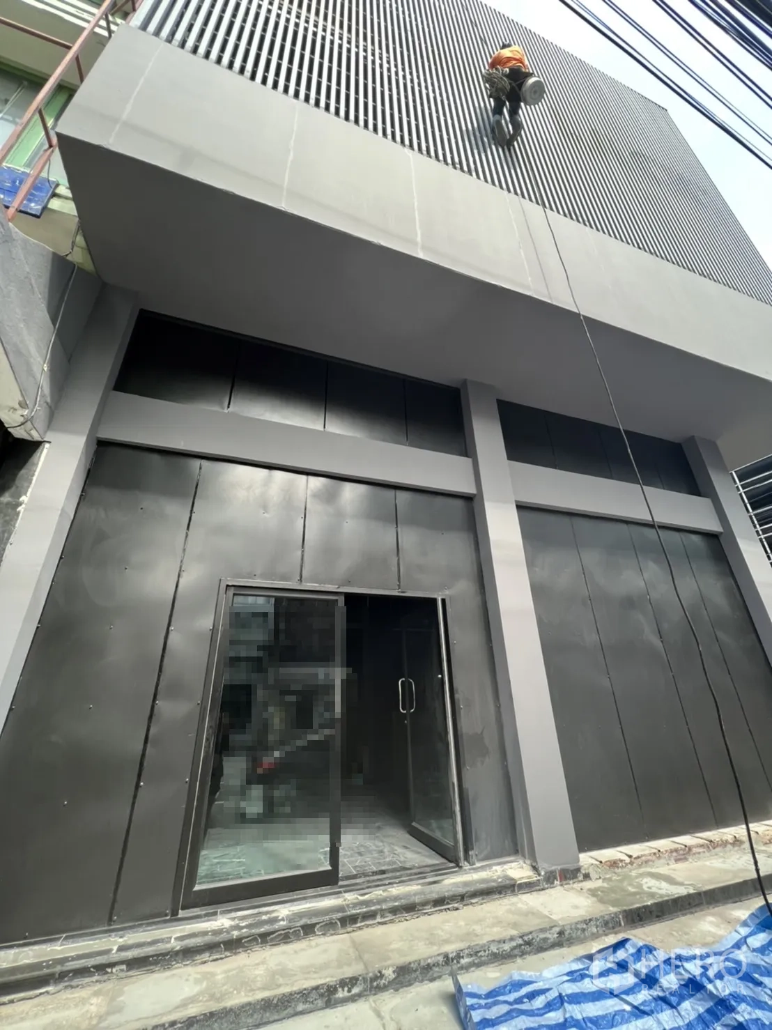Home Office for rent or sale in Khlong Toei, Bangkok - Modern black facade with glass entrance and vertical louvered cladding.