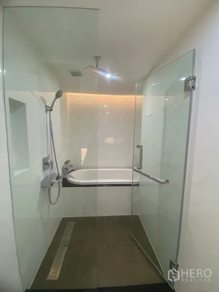 Apartment for rent in Watthana, Bangkok - Modern bathroom featuring a glass shower enclosure with rainfall shower and a soaking bathtub behind the partition.