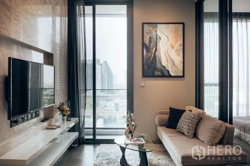 คอนโด ให้เช่าหรือขายในHuai Khwang, Bangkok - ห้องนั่งเล่นสไตล์โมเดิร์น ผนังทีวูลายหินอ่อน ประตูกระจกสูงเปิดสู่ระเบียงวิวเมือง