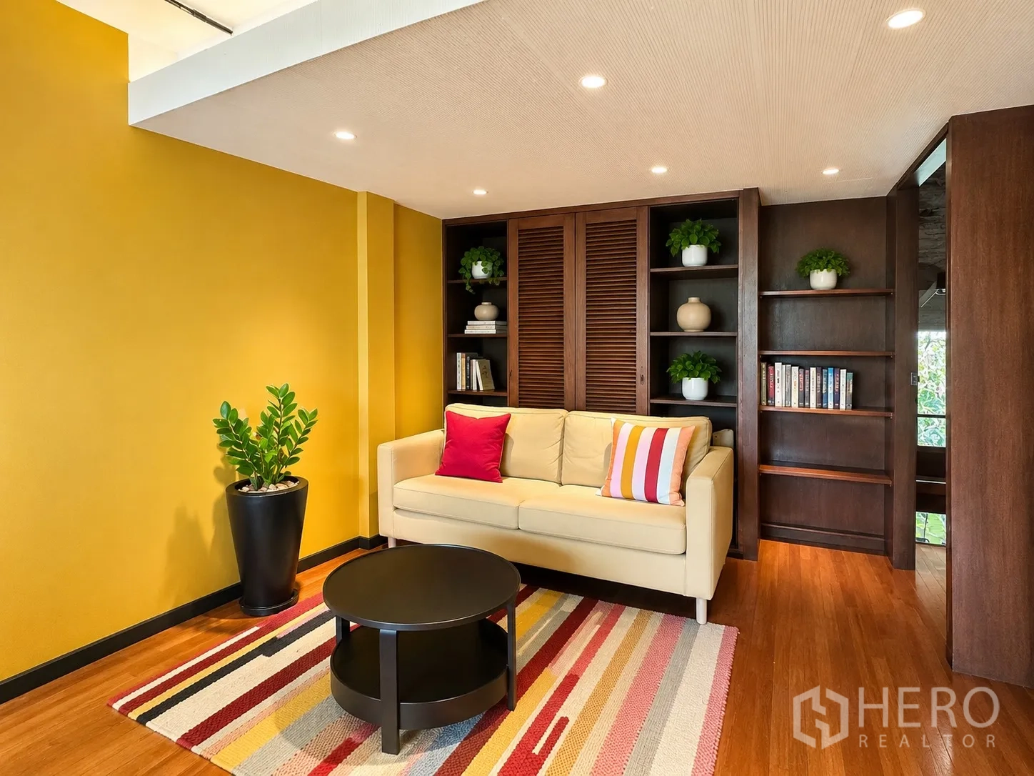 Office Space for rent in Phaya Thai, Bangkok - Colorful lounge with yellow wall, cream sofa, and built-in bookcases.