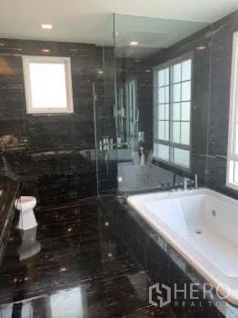 Detached House for sale in Bang Phli, Samut Prakan - Luxurious bathroom clad in dark marble with a soaking tub, glass-enclosed shower, and windows.