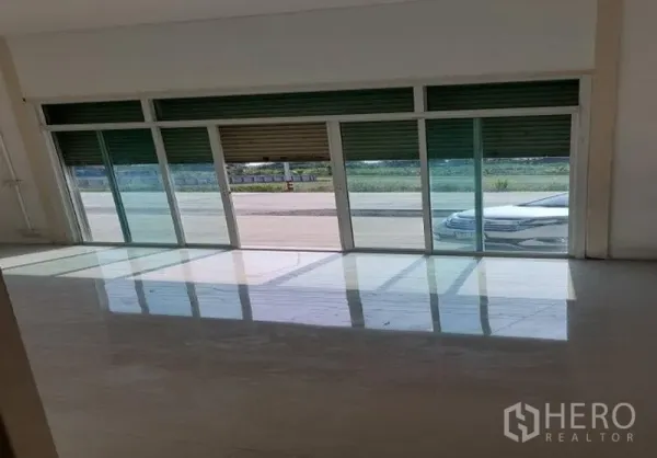 Factory for rent in Pathum Thani - Bright front office area with glass sliding doors and a high roller shutter opening to the roadside.