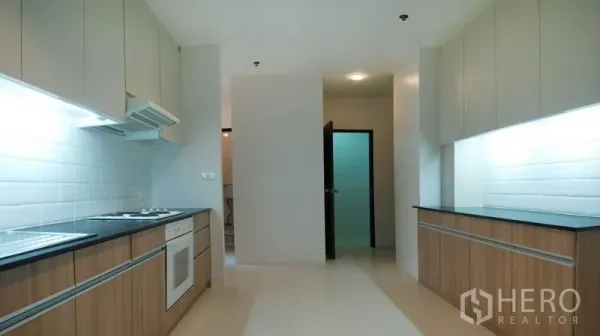 公寓 出租在Watthana, Bangkok - 宽敞走廊式厨房，双排台面、烤箱与白色地铁砖挡板