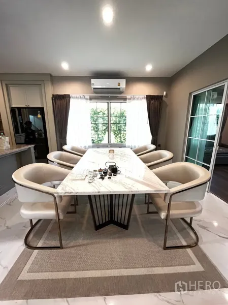 Detached House for rent or sale in Bang Khen, Bangkok - Dining area featuring a long marble table, cushioned chairs and garden views.