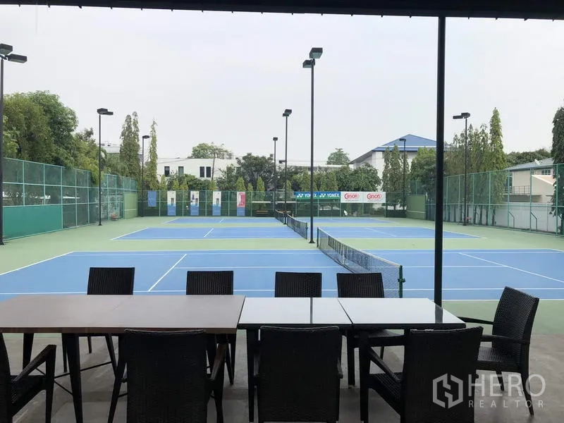 Detached House for rent in Khan Na Yao, Bangkok - Community tennis courts with lighting and a shaded seating area beside the courts.