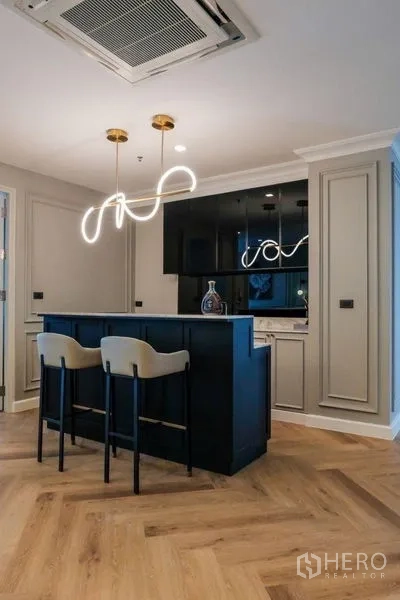 Condominium for rent in Khlong Luang, Pathum Thani - Open kitchen with navy island, bar stools and sculptural pendant lights.