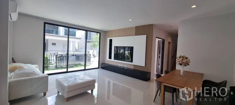 Detached House for rent in Saphan Sung, Bangkok - Open-plan living room with large sliding doors and a built-in TV feature wall.