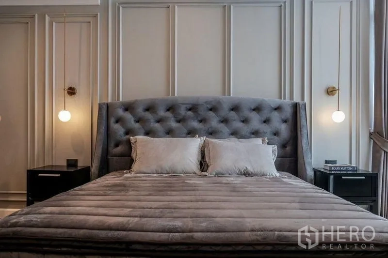 Condominium for rent in Khlong Luang, Pathum Thani - Primary bedroom with tufted headboard, pendant lamps and wall paneling.