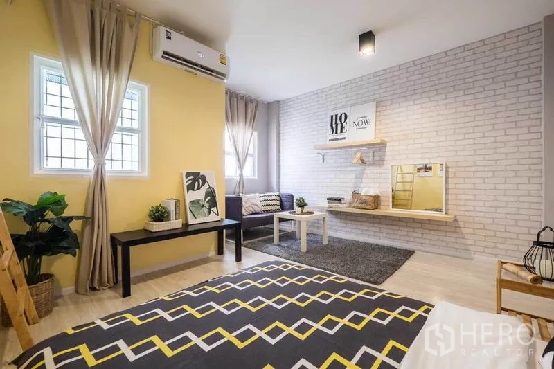 Detached House for rent in Khlong Toei, Bangkok - Bright bedroom with chevron rug, brick accent wall, seating nook and air-conditioning.