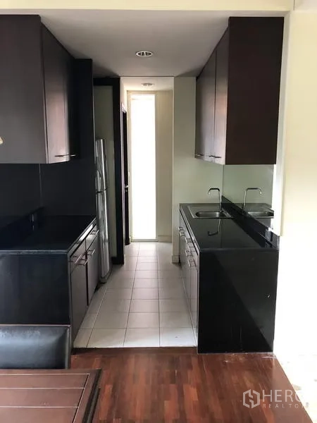 Detached House for sale in Wang Thonglang, Bangkok - Galley kitchen with dark cabinetry, black stone countertops, and a double sink.