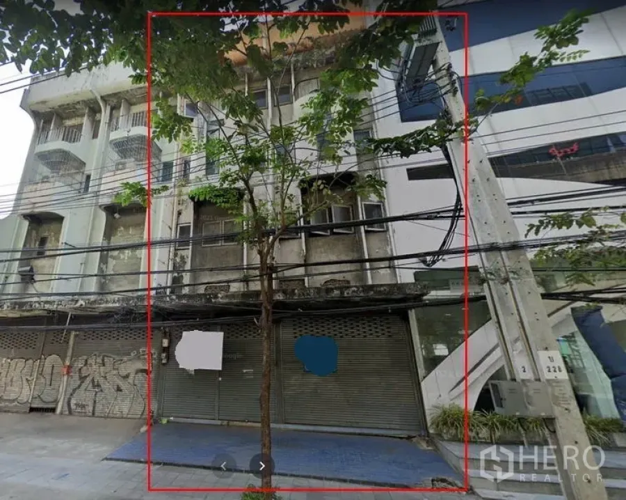 Shophouse for rent in Bang Na, Bangkok - Street-facing multi-storey shophouse facade with metal roller shutters, sidewalk and power lines in Phra Khanong.