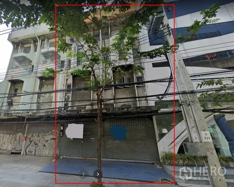 Shophouse for rent in Bang Na, Bangkok - Street-facing multi-storey shophouse facade with metal roller shutters, sidewalk and power lines in Phra Khanong.
