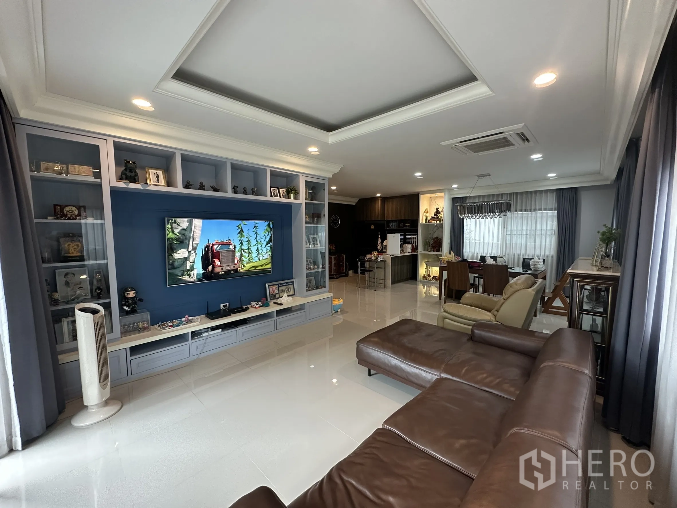 Detached House for rent in Lam Luk Ka, Pathum Thani - Bright lounge with blue media cabinetry, recessed ceiling and dining area.