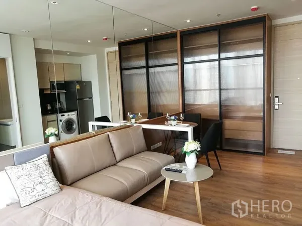 Condominium for sale in Khlong Toei, Bangkok - Living area with leather sofa, round side table, built-in wardrobe and dining table.