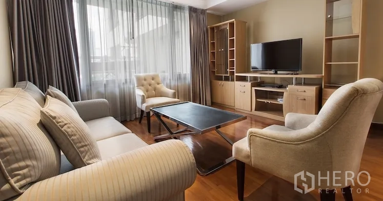Condominium for rent in Sathon, Bangkok - Living area view with TV console, shelving, sofa set and floor-to-ceiling drapes.