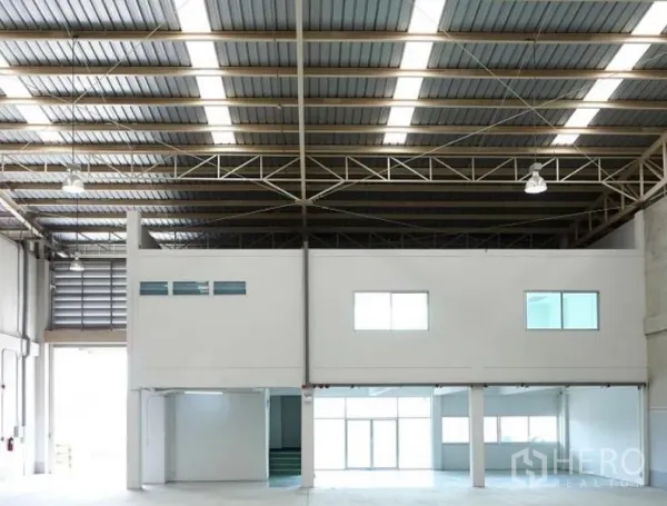Factory for rent in Pluak Daeng, Rayong - Wide warehouse bay with mezzanine office, bright strip lighting and large loading entrance.