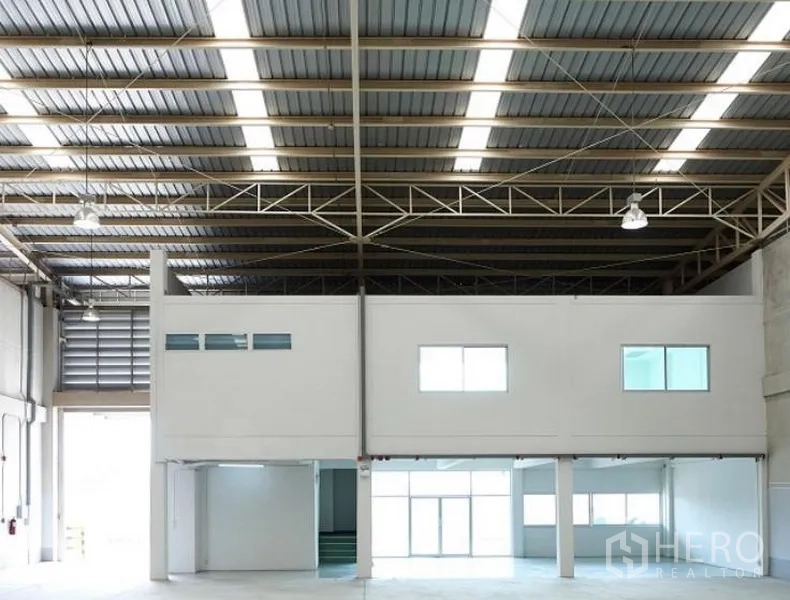 Factory for rent in Pluak Daeng, Rayong - Wide warehouse bay with mezzanine office, bright strip lighting and large loading entrance.