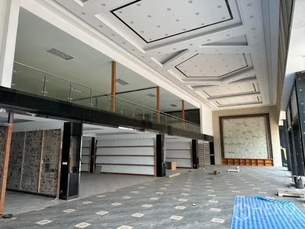 Warehouse for rent in Lam Luk Ka, Pathum Thani - Double-height showroom interior with coffered ceiling, glass mezzanine, and tiled floors.