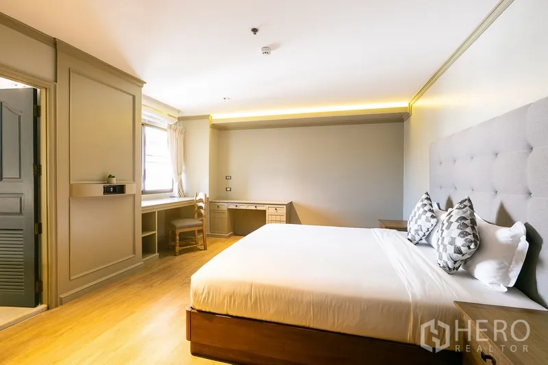 Apartment for rent in Khlong Toei, Bangkok - Another view of the second bedroom with upholstered headboard, study desk, and warm cove lighting.