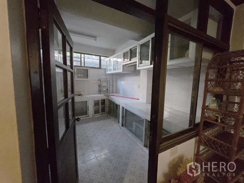 Home Office for rent in Sathon, Bangkok - Enclosed Thai kitchen with tiled countertops, glass-front cabinets and floor tiles.