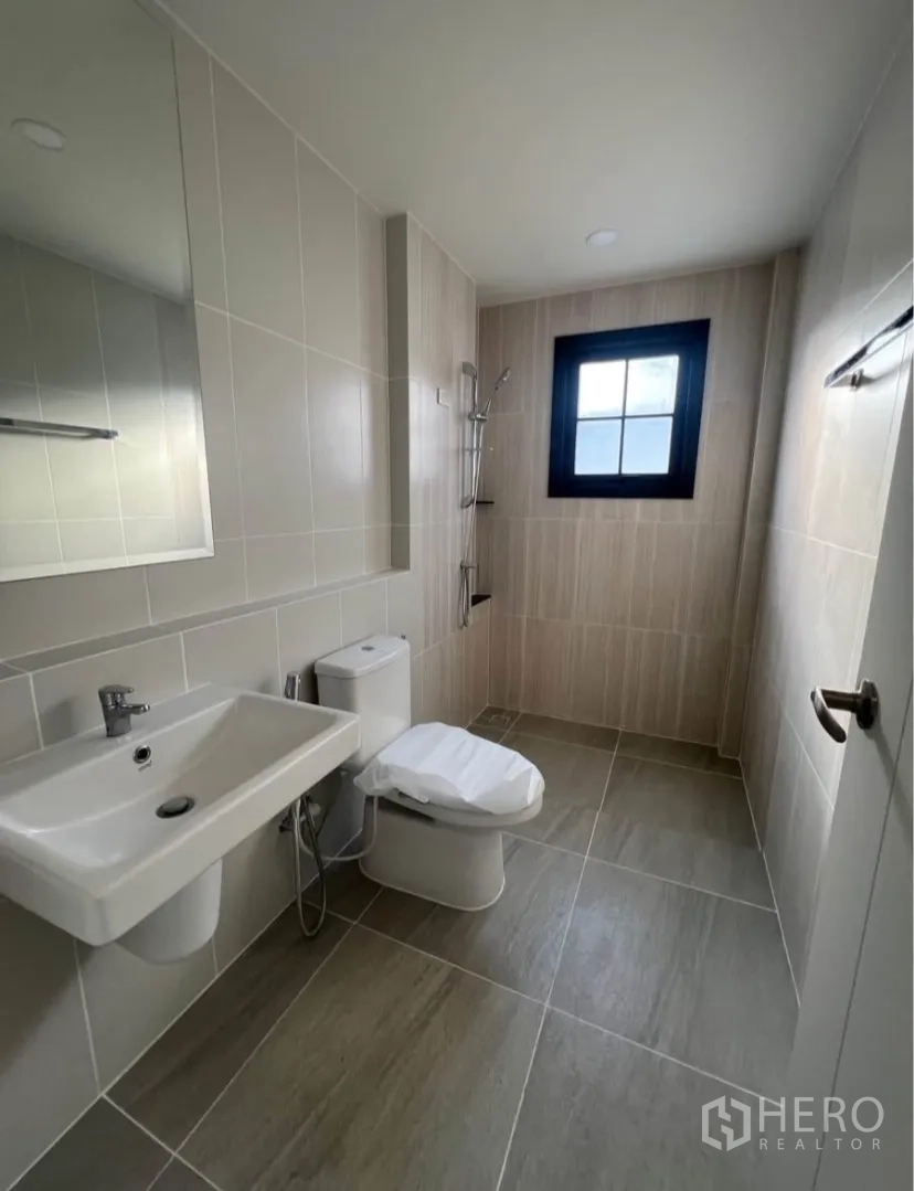 独栋房屋 for rent in Bang Phli, Samut Prakan - 浅米色瓷砖卫浴，步入式淋浴、台盆、坐便器与窗户。