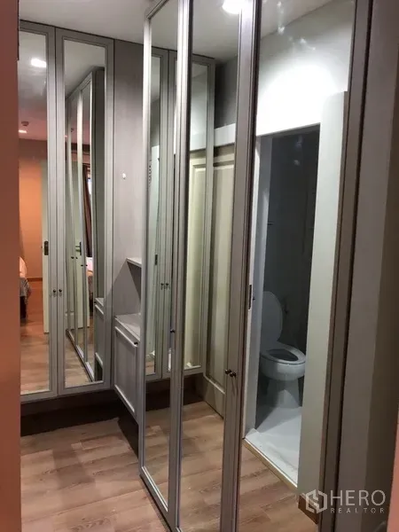 Condominium for rent in Pathum Wan, Bangkok - Hallway dressing area with mirrored wardrobes leading to the bathroom.