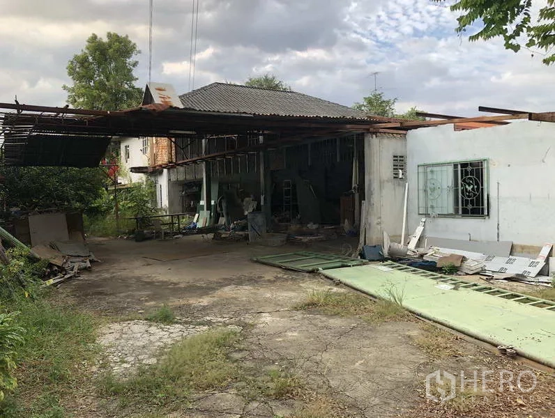 คลังสินค้า ให้เช่าในSai Mai, Bangkok - ภายนอกโกดังสภาพเดิมหลังคาเมทัลชีท ลานกว้างและทางเข้าคอนกรีตที่แตกร้าวบางส่วน
