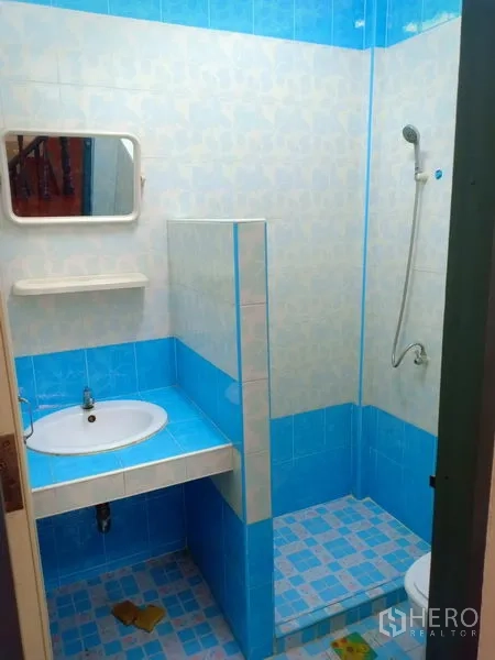 Townhouse for rent in Phra Khanong, Bangkok - Blue-tiled bathroom featuring a vanity sink, mirror and walk-in shower.
