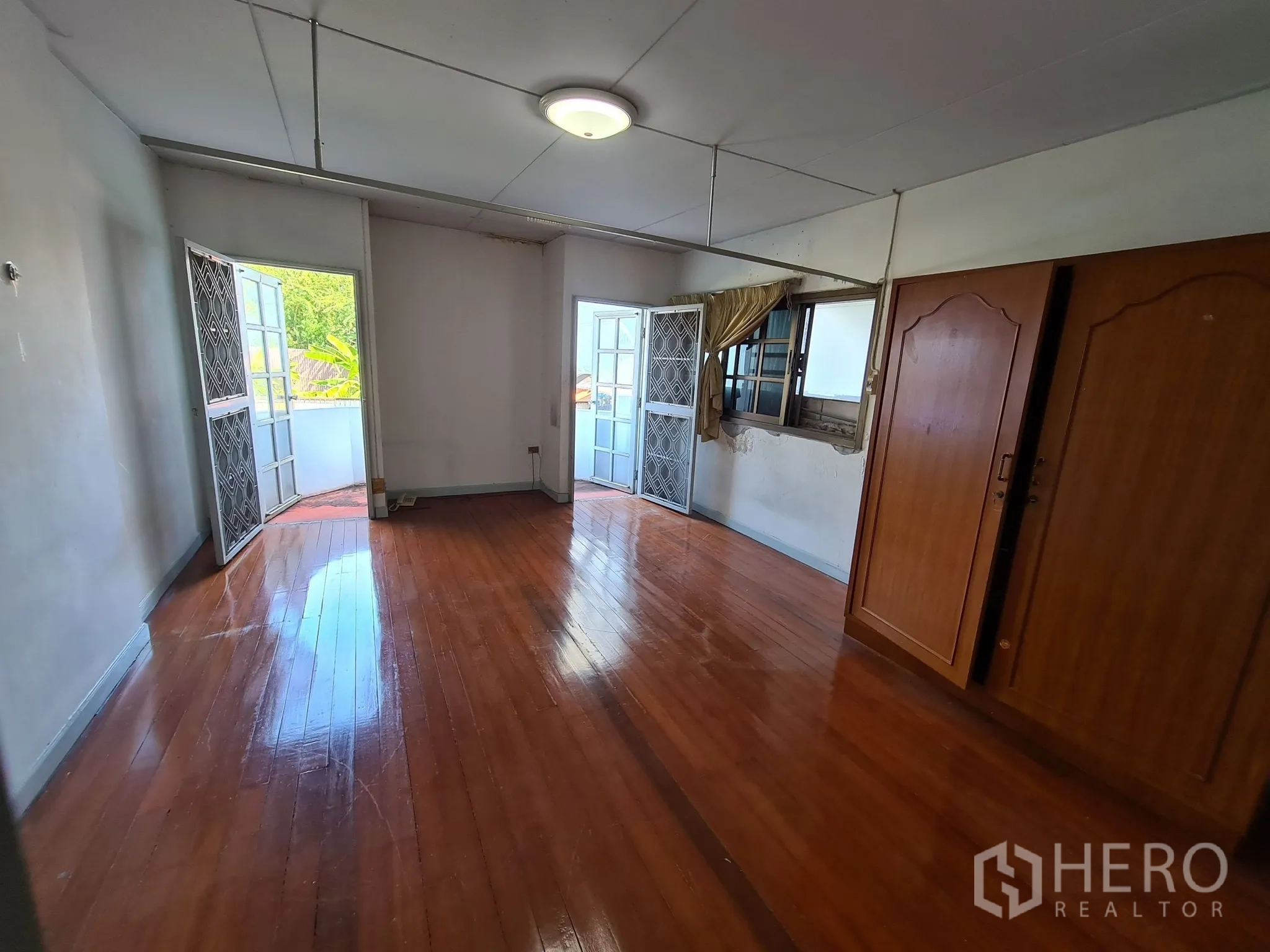 Detached House for sale in Chatuchak, Bangkok - Wood-floored bedroom with twin balcony doors and wardrobes.