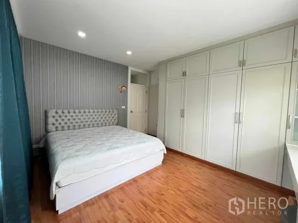 Detached House for sale in Bang Kruai, Nonthaburi - Master bedroom with large fitted wardrobes, king bed, wood flooring, and recessed lighting.