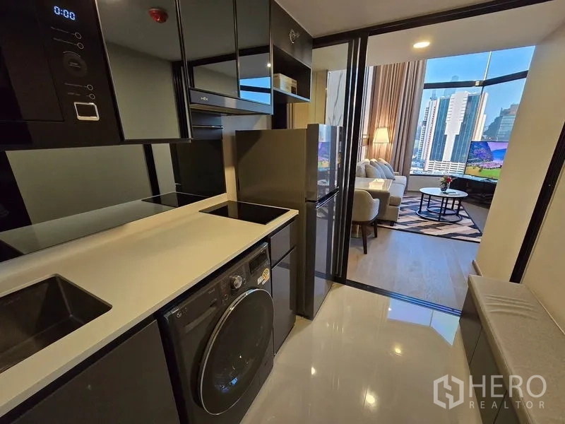 Condominium for rent - Sleek galley kitchen with induction cooktop, washer-dryer, and a view toward the living room and city.