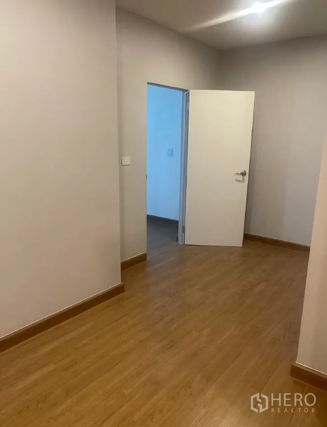 Detached House for rent or sale in Saphan Sung, Bangkok - Empty bedroom with wood flooring and a white door.