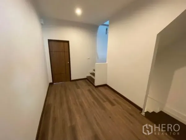 Townhouse for rent in Bang Na, Bangkok - Upper-floor hallway with wood floors, storage door and staircase.