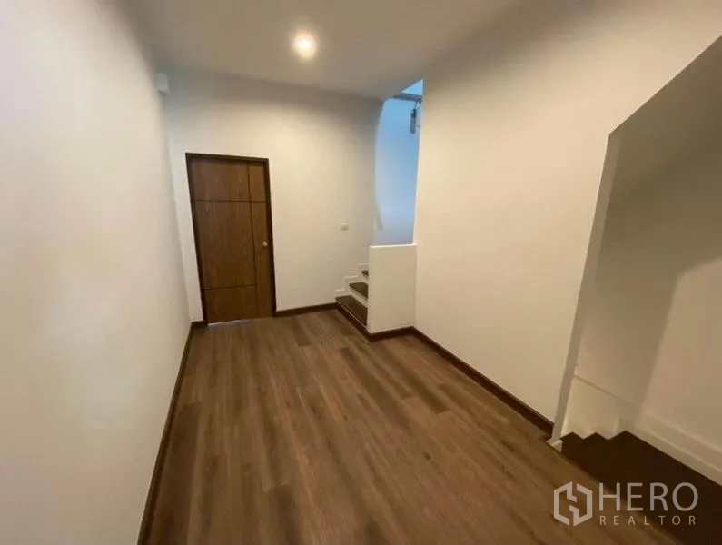 Townhouse for rent in Bang Na, Bangkok - Upper-floor hallway with wood floors, storage door and staircase.